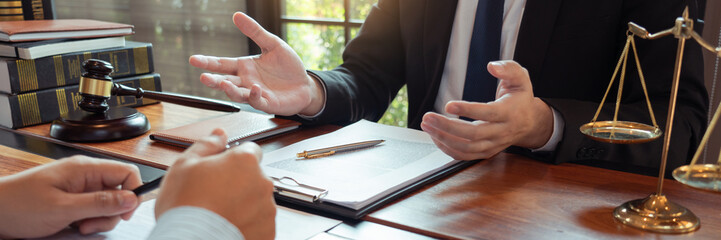 Lawyer working with client discussing contract papers with brass scale about legal legislation in...
