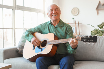 Elderly man playing guitar at home