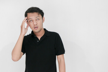 Portrait of young asian man isolated on grey background suffering from severe headache, pressing...