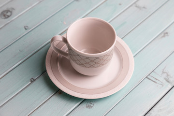 White porcelain coffee Cup on a turquoise wooden table. Still life in pastel colors.