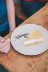 Man wear blue t-shirt sitting in coffee shop eating lemon cheesecake in white plate with folk.Tasty fresh homemade cream cheese sweet cake for breakfast.Eat delicious dessert is good for your mood. 