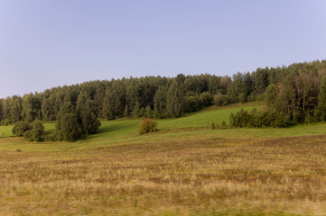 Soft landsсape with yellow meadows and forests far away. Light blue sky. Fall fields 