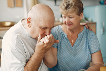 Coyple in a kitchen. Grandparents sitting at home. Woman with vegetables