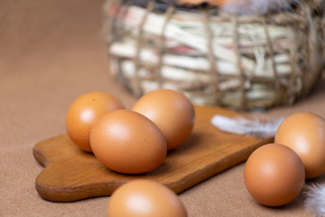 Fresh natural chicken eggs on a brown background with a basket