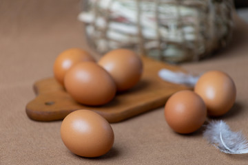 Fresh natural chicken eggs on a brown background with a basket