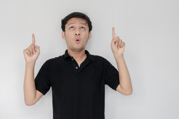 Happy and smile of young Asian man with hand point on empty space.  Indonesia Man wear black shirt Isolated grey background.