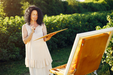 Woman artist painting with oil. Paints in a field