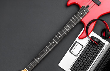 Electric guitar with laptop and headphones on black. Writing music. Top view. Space for text.