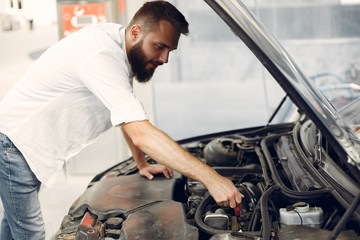 Man checks the engine. Guy checks his car Male in a white shirt.