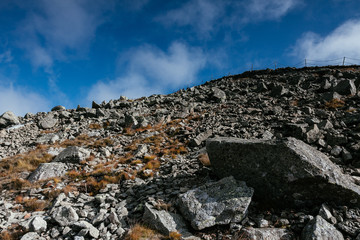 Rocks and stones on mountain slope with blue sky