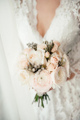 The bride in a nightgown holds a beautiful wedding bouquet in her hands