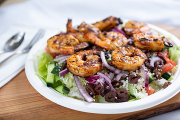 A view of a Greek shrimp salad, in a restaurant or kitchen setting.