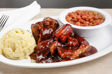 A view of a plate of barbecue rib tips with sauce, in a restaurant or kitchen setting.