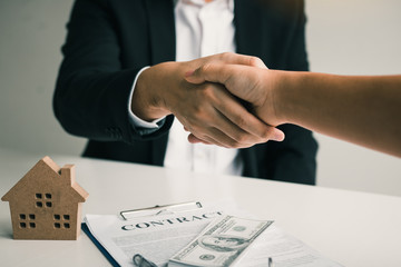 Home sales agents and buyers work on signing new homes and shaking hands.