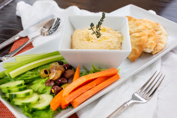 A view of a hummus platter, in a restaurant or kitchen setting.
