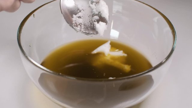Close up of home made ointment creating process. Adding thick coconut oil into herbal oil base. 4K resolution