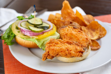 A view of an open faced fried chicken sandwich, in a restaurant or kitchen setting.