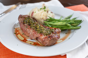 A view of a plate of New York strip steak, in a restaurant or kitchen setting.
