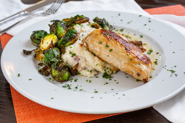 A view of a plate of roasted chicken in a restaurant or kitchen setting.