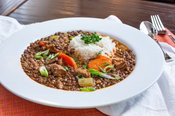 A view of a plate of lentil and chicken stew, in a restaurant or kitchen setting.