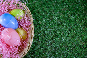 Easter eggs on a basket with grass and green background for happy easter celebration