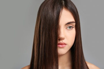 Naklejka premium Young woman with beautiful straight hair on grey background
