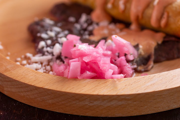 A closeup view of a pile of chopped pickled red onions, on an entree plate, in a restaurant or kitchen setting.
