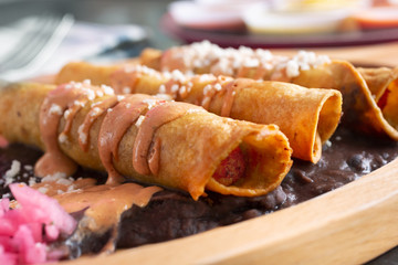 A closeup view of a plate of taquitos, in a restaurant or kitchen setting.