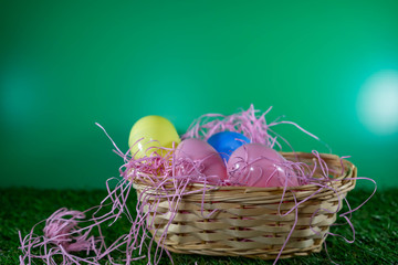 Easter eggs on a basket with grass and green background for happy easter celebration