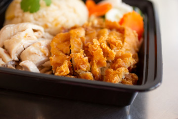 A closeup view of a Hainanese and crispy chicken combination entree, in a restaurant or kitchen setting.