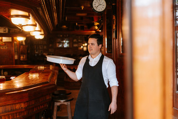 
A young waiter with a tray in a cafe