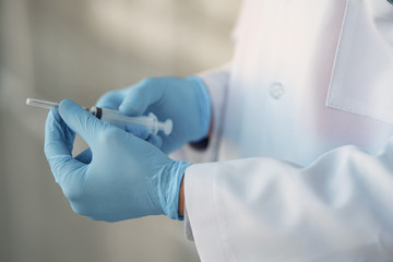 Medical student with a syringe. Person in a white uniform. Coronavirus theme.