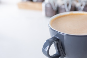 A closeup view of a mocha latte coffee mug on the right side of the frame, in a cafe setting.