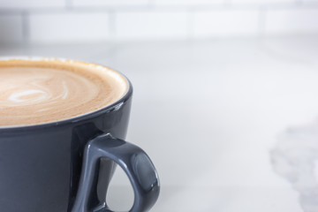 A closeup view of a mocha latte coffee mug on the left side of the frame in a cafe setting.