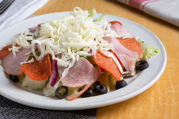 A closeup view of a plate of antipasto salad in a restaurant or kitchen setting.