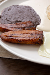 A closeup view of fried plantains on a latin breakfast plate in a restaurant or kitchen setting.