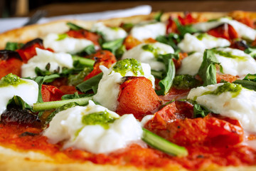 A closeup view of a margherita pizza pie, in a restaurant or kitchen setting. 