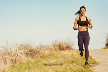 Young muscular build woman having sports training and running in nature