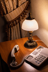 Phone on the table next to the lamp.
Hotel interior.
Sleeping room with a old telephone, do not...