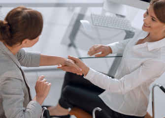 Fototapeta premium view from the top.business woman shakes hands with the officer sitting near the desktop