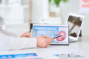 Urologist with clipboard at table in clinic
