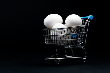 chicken white eggs in a shopping cart. isolated on black