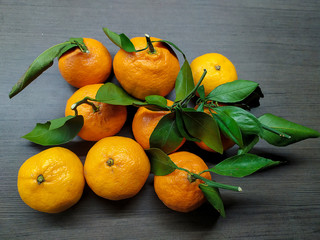 Orange ripe tangerines with green leaves on a dark background