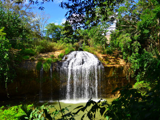 Fototapeta na wymiar A beautiful waterfall in Vietnam in sunny warm summer day and a lot of green trees around