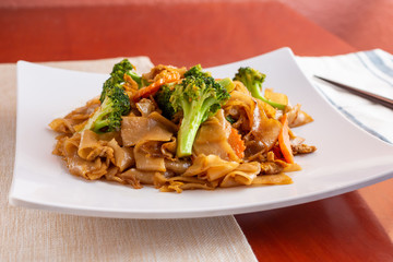 A view of a plate of Thai Pad See Ew in a restaurant or kitchen setting.