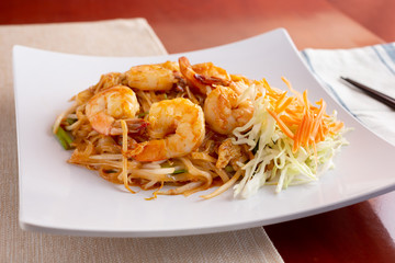 A view of a plate of shrimp pad Thai in a restaurant or kitchen setting.
