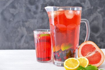 Jug and glass of tasty cold tea on table