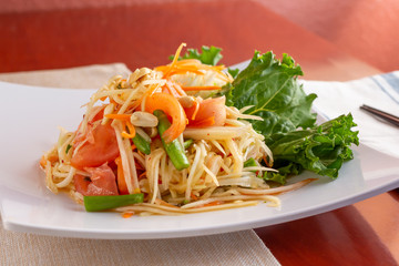 A view of a plate of papaya salad in a kitchen or restaurant setting.
