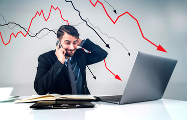 Shocked businessman with laptop, falling graph