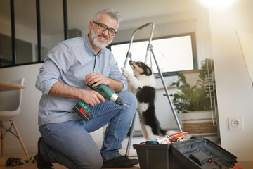 Man at home doing do-it-yourself work with puppy around